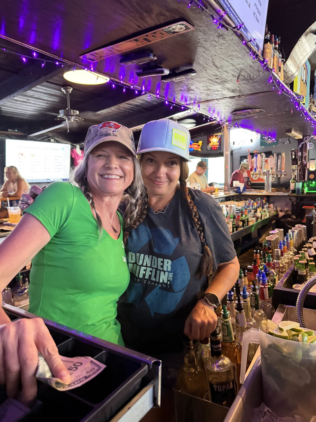 Two smiling bartenders behind the bar at Kelly's