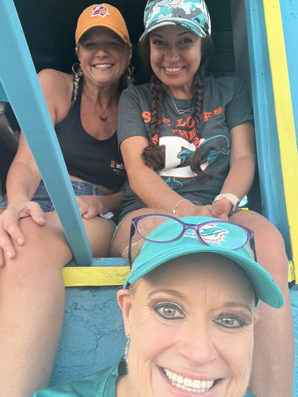 Three friends at the teal porch railing outside Kelly's