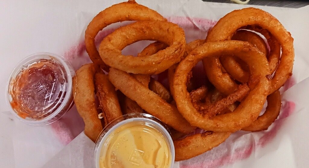 Basket of beer-battered onion rings with two dipping sauces
