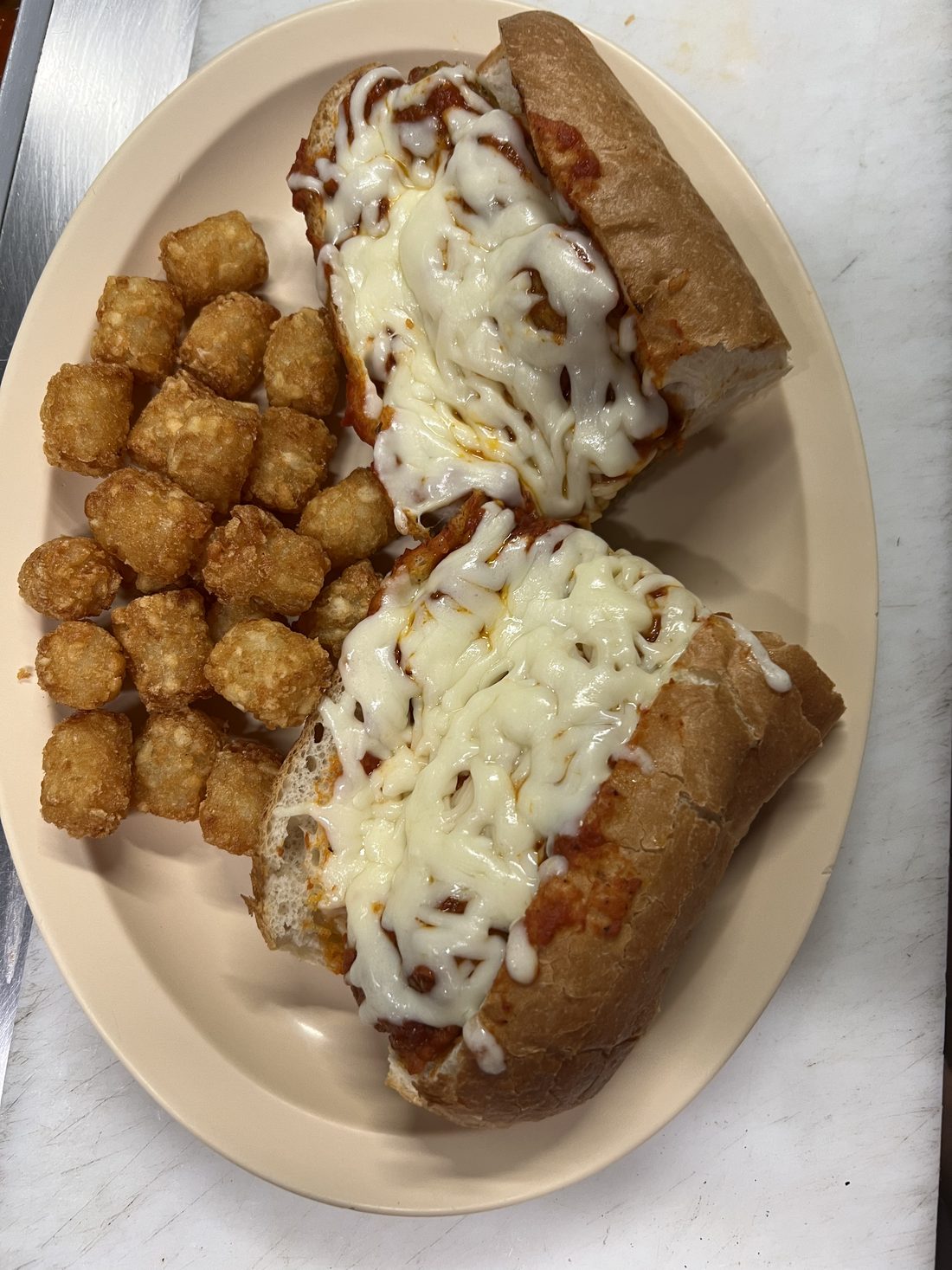 Chicken parm sub with a side of tater tots