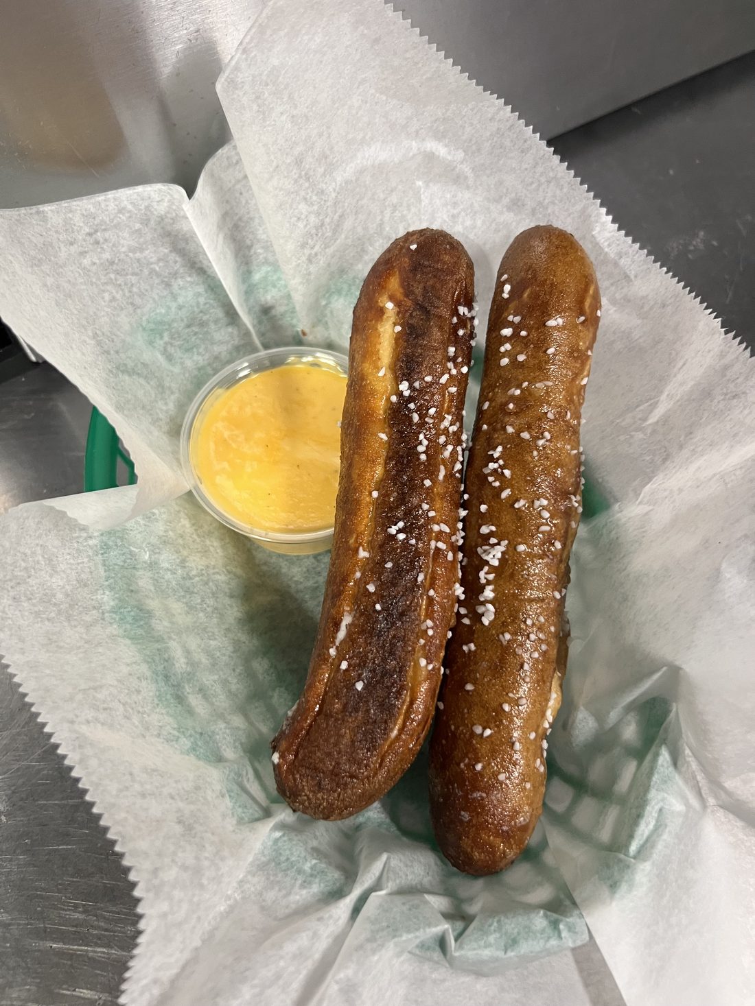 Two salted soft pretzel sticks with beer cheese