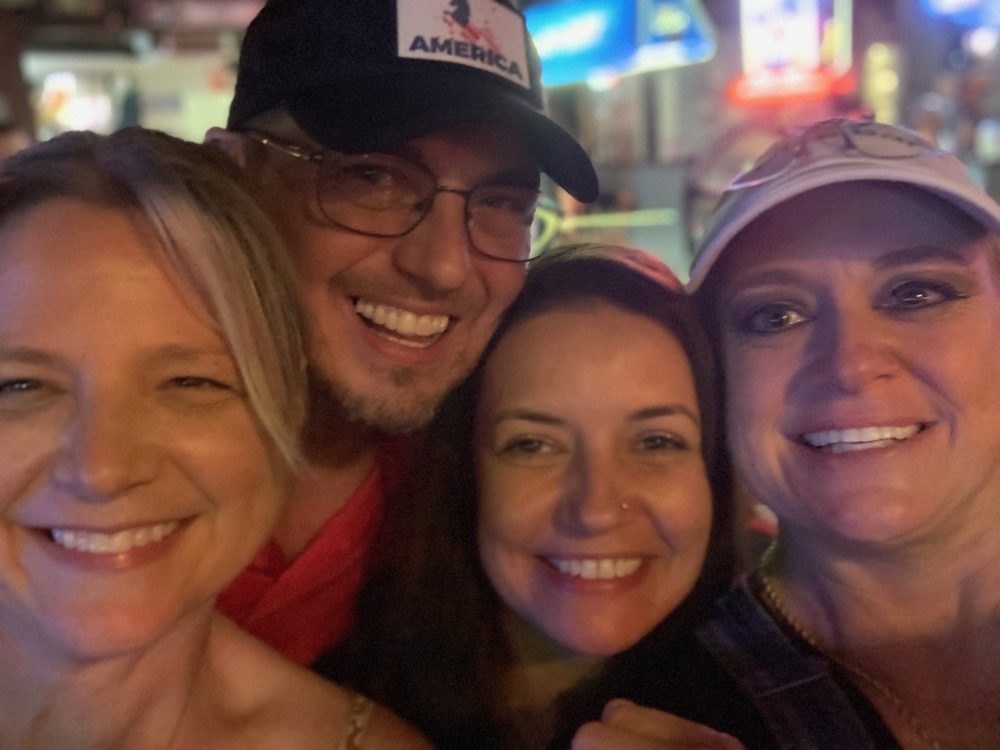 Four friends squeezed into a selfie under the neon