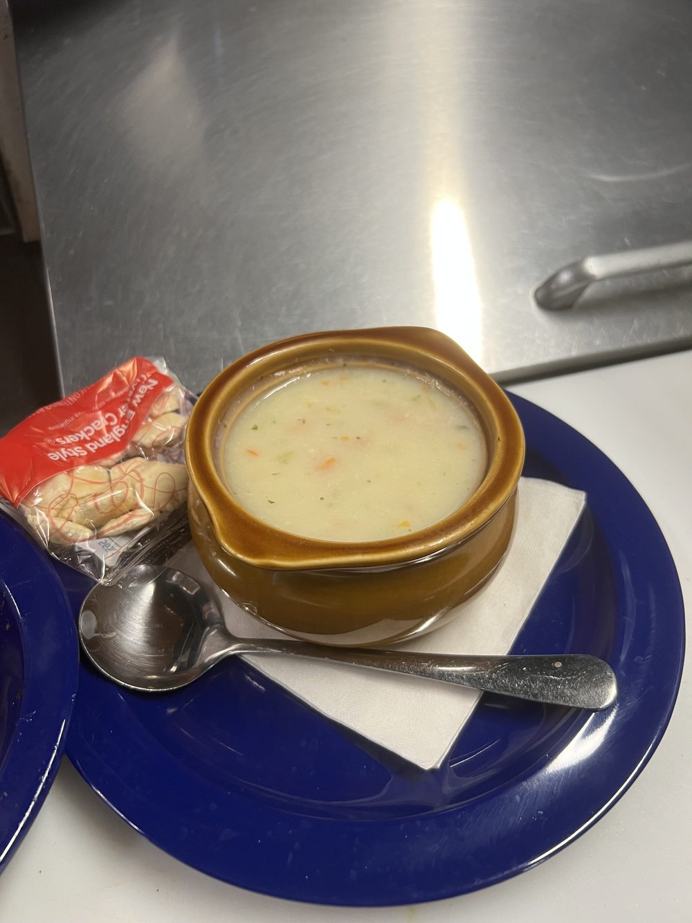 Crock of homemade soup with oyster crackers and a spoon