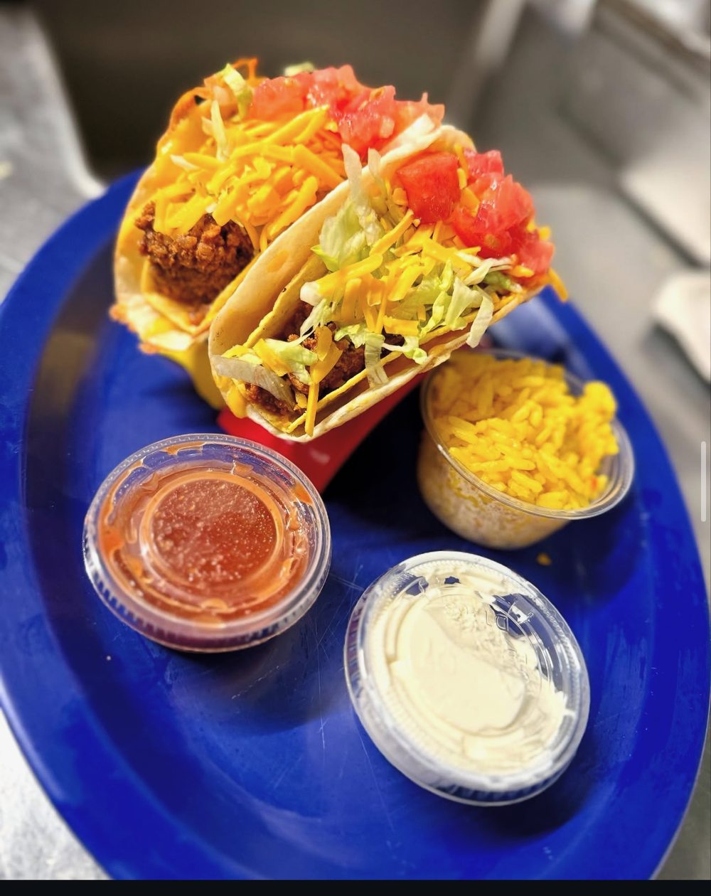 Two tacos with yellow rice, salsa and sour cream